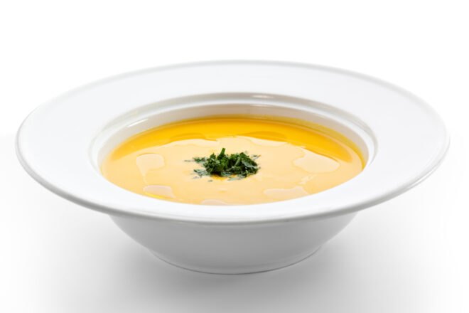 yellow soup in white bowl on white background
