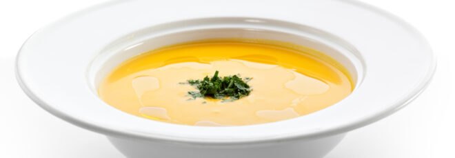 yellow soup in white bowl on white background