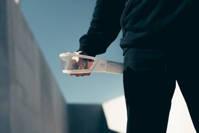 man holding white mask with clear window in hand