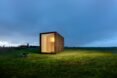 tiny black cabin illuminated in the evening time