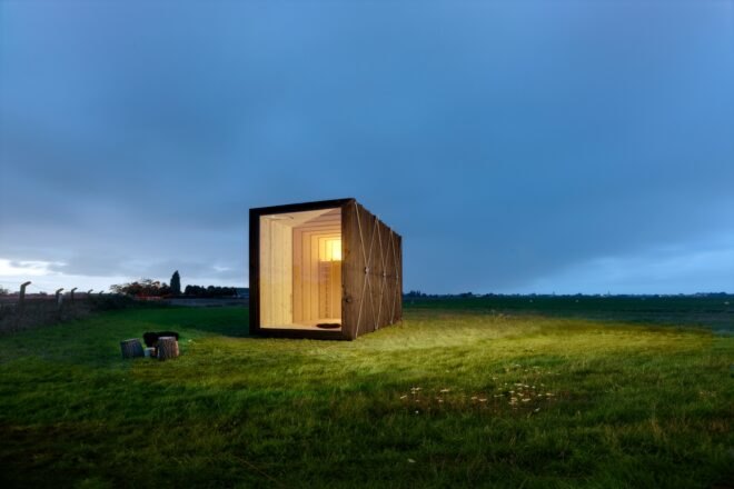 tiny black cabin illuminated in the evening time