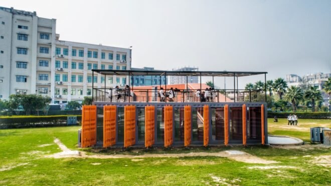 shipping container building with bright orange window louvers