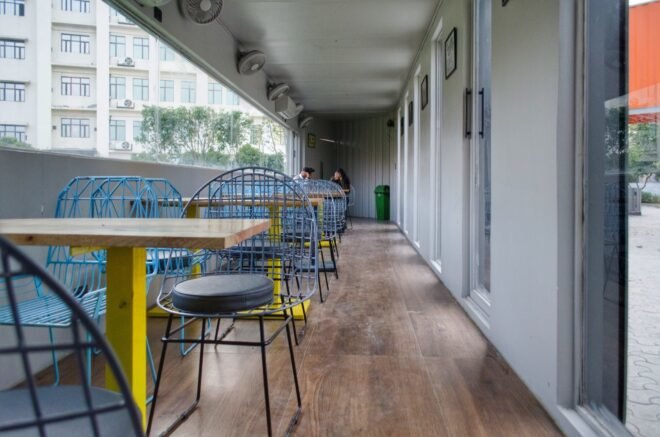 wood and yellow dining tables and chairs in a narrow cafe