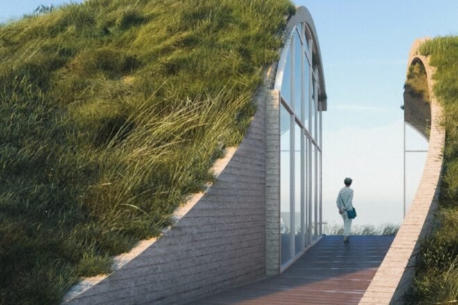 a person walking through a walkway between green hills