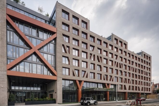 streetview of a building with windowed facades and red cross-bracing