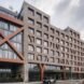 streetview of a building with windowed facades and red cross-bracing