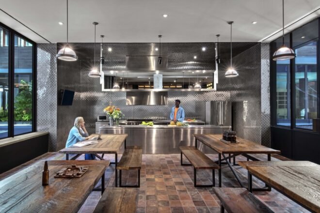 a communal kitchen area with steel and people lounging