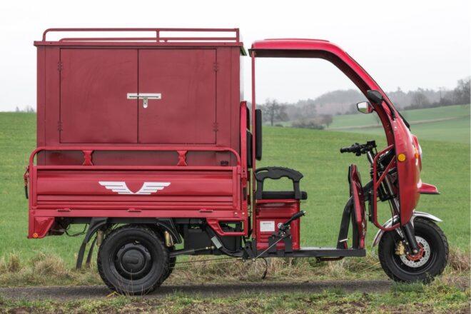 side view of red electric truck with three wheels