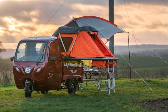 red, three-wheeled camper with attached orange tent