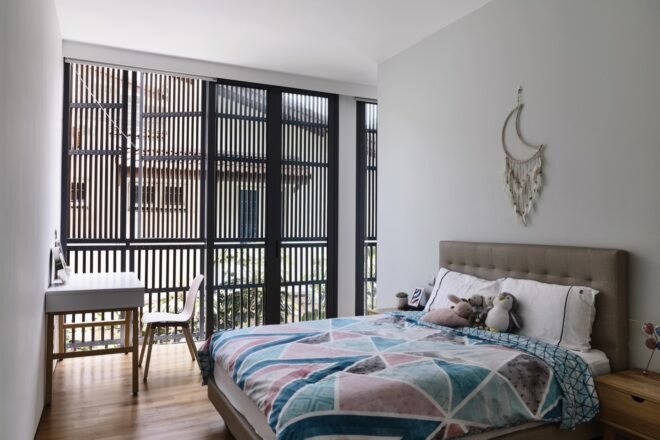 multicolored bed in large white room with windows covered by timber slats