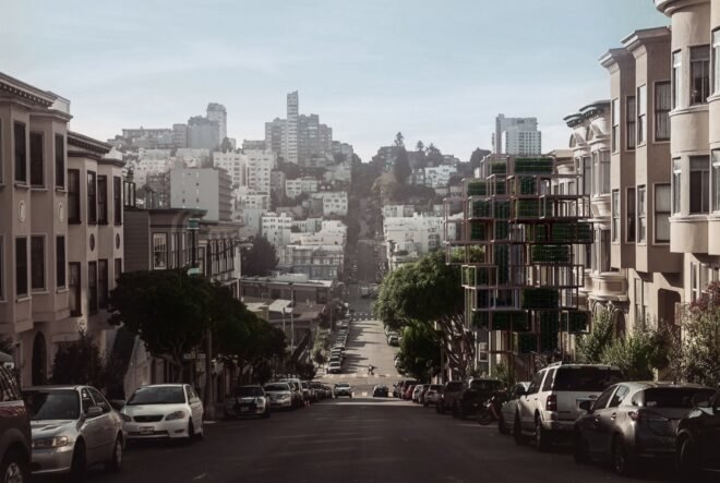 a shot from the middle of a street, looking down a hill in a city-scape. the Glasir tree is on the right side of the street