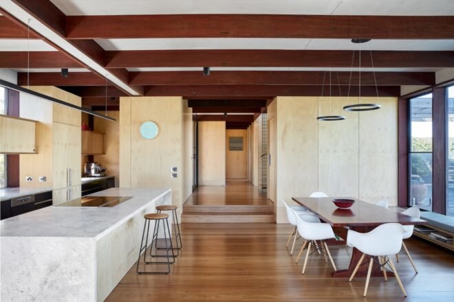 dark wood dining table in front of kitchen with plywood cabinetry