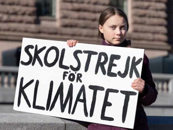 Greta Thunberg demonstrating in Stockholm on Fridays. Holding a sign that says "School strike for Climate"
