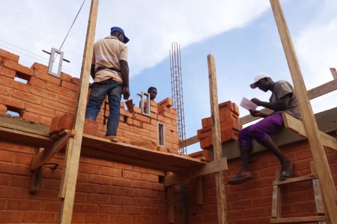 people constructing a building from earth bricks
