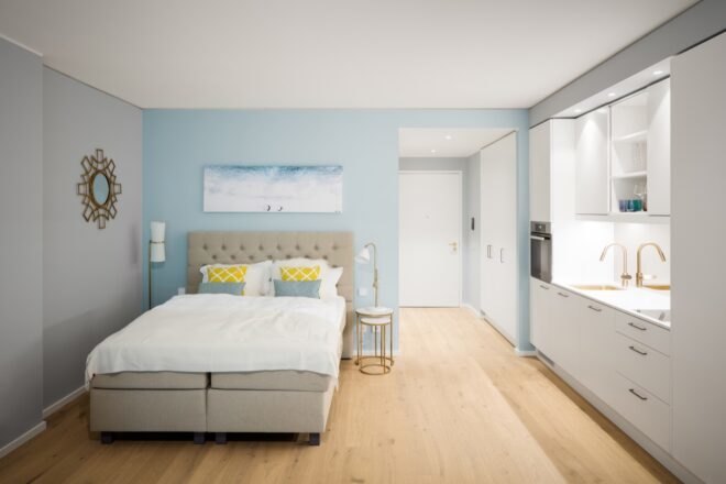 white and light blue bedroom with a gray tufted headboard and large windows