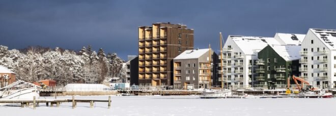 tall dark wood building alongside white gabled buildings