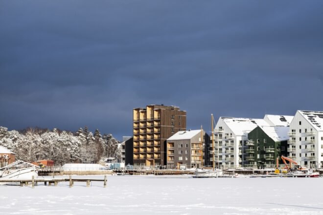 tall dark wood building alongside white gabled buildings