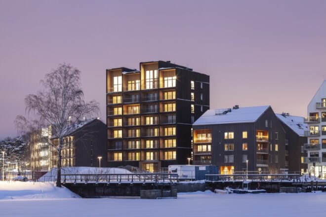 tall dark wood building lit from within at night