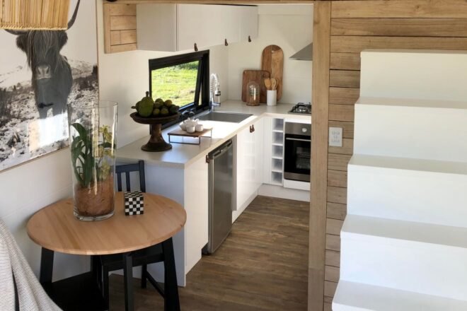 white kitchen of tiny home with stairs leading up to sleeping loft