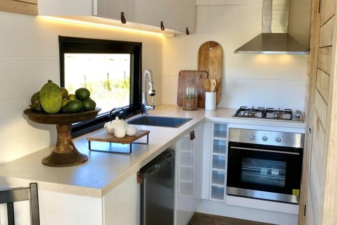 tiny home kitchen with white cabinets and full-sized stove
