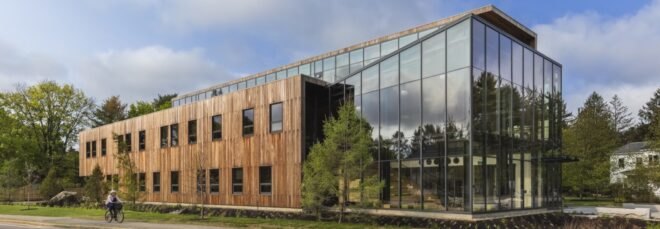 a building with one half of the facade covered in wood and the other made of glass