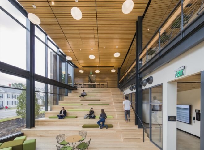 an interior shot of wooden steps where some people walk and some sit and study