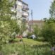 a green space with people lounging on the grass and a tall building in the background
