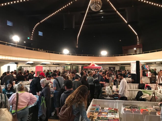 people looking at vegan food booths inside a conference center