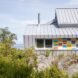 white home with dual pitched roofs and colorful siding