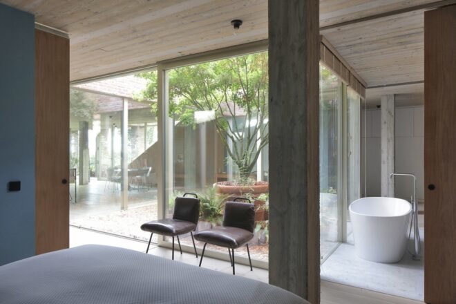 bed facing glass walls with views of a courtyard