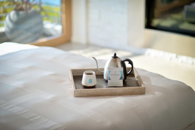 kettle, mug and package of a coffee bag on a tray on a hotel bed