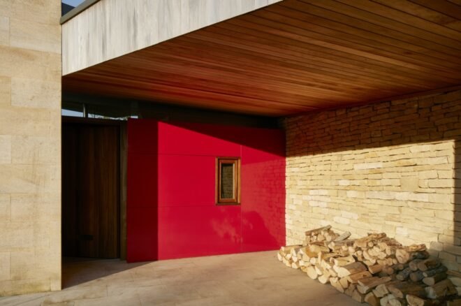 a red entranceway with a pile of wood stacked off to the side