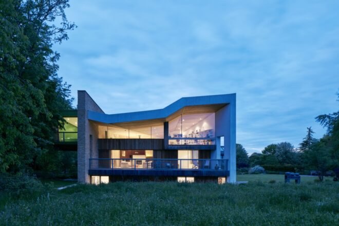 a grassy area in front of the building with floor-to-ceiling windows through which natural light filters out