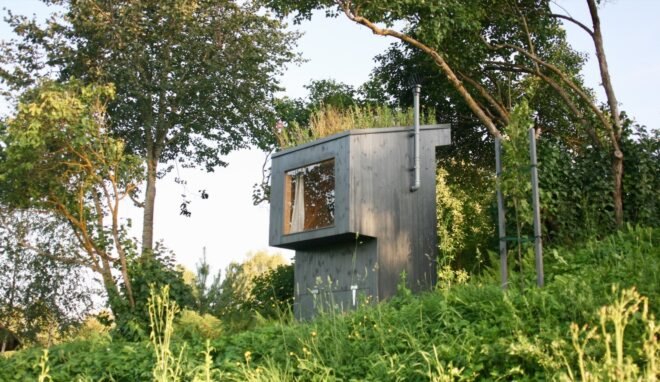 black outhouse with grassy roof