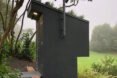 tall wood outhouse with grassy roof