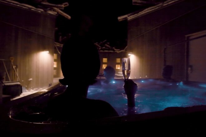 person with champagne flute in a pool at night