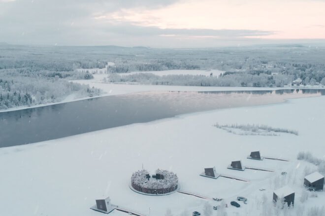 a circular building and several cabins on a frozen landscape