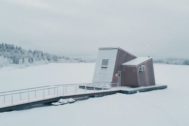 a wooden cabin with slanted volume on a frozen landscape