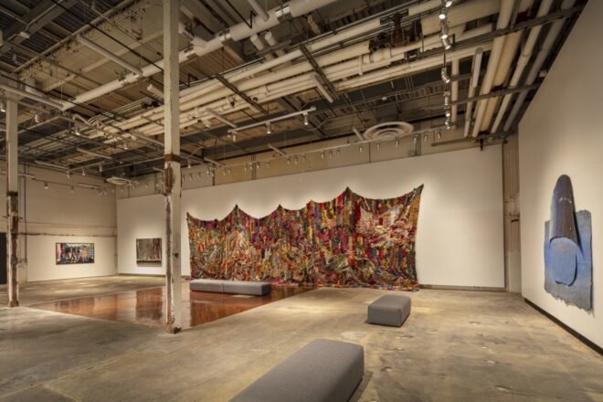 colorful cloth draped from a white wall inside a museum