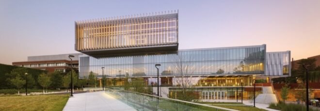 large glass college building at dusk