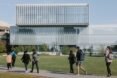 students walking on path outside large glass building