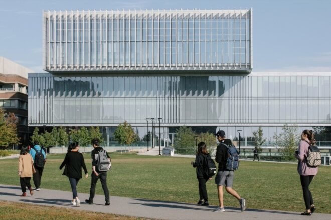 students walking on path outside large glass building