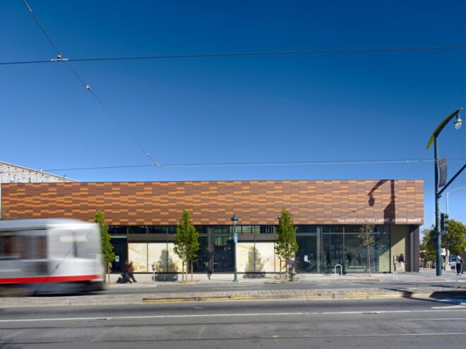 bus driving past a wood library with several windows