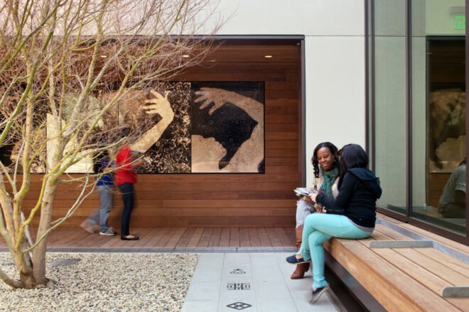 people sitting on wood bench outside a wood library