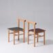 two oak wood chairs with black and red seats