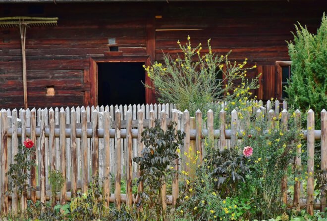 a fence in a garden in front of a wood building
