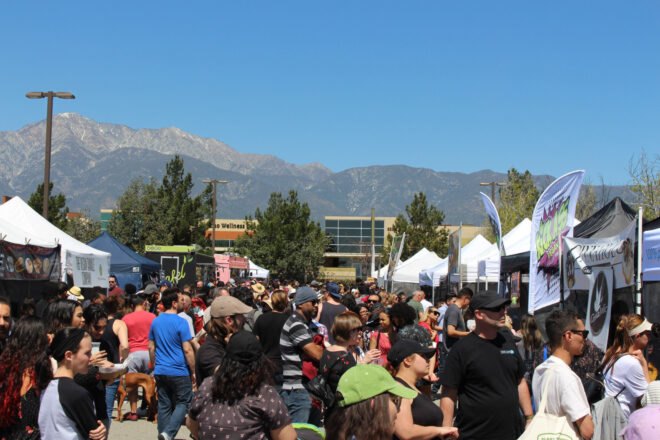 people waiting in lines for vegan food with mountains in background