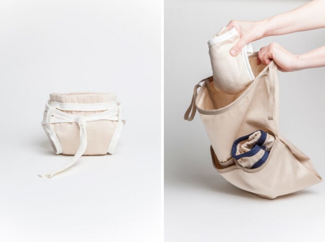 person putting a tan reusable diaper into a tan cloth bag