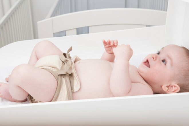 baby wearing a reusable diaper and lying on a changing table