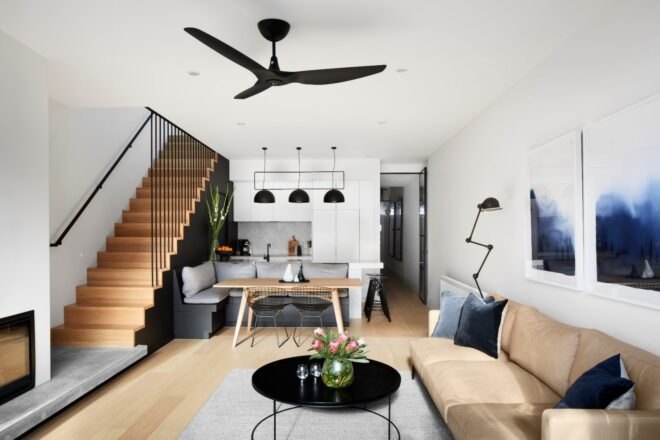 tan sofa, black round coffee table and wooden staircase